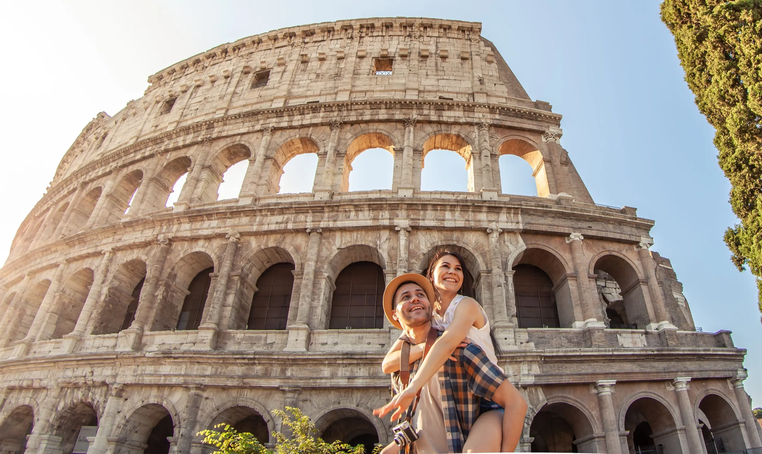 Young happy couple having fun at Colosseum, Rome. Piggyback posing for pictures.