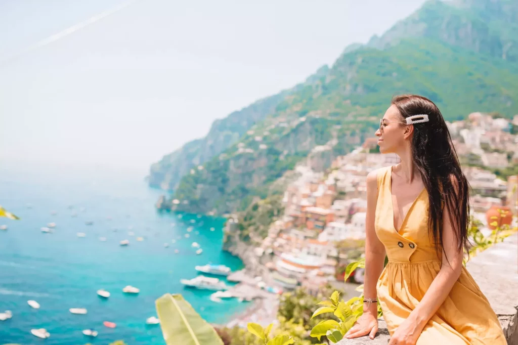 Young woman in yellow dress with Positano village on the background, Amalfi Coast, Italy